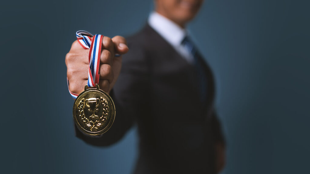 Man in a suit holding out a medal in his fist