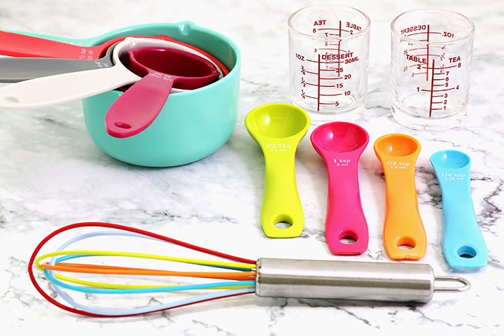 Measuring cups, measuring spoons, and a whisk sitting neatly on a counter.