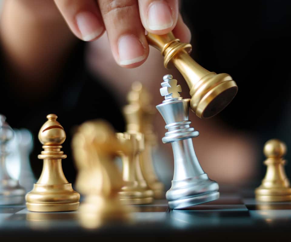 Close up shot hand of business woman moving golden chess to defeat and kill silver king chess on white and black chess board for business challenge competition winner and loser concept, selective focus on king chess shallow depth of field